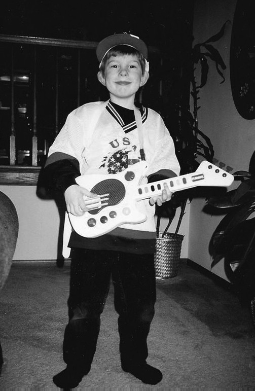 A young guitarist getting started, holding a toy guitar